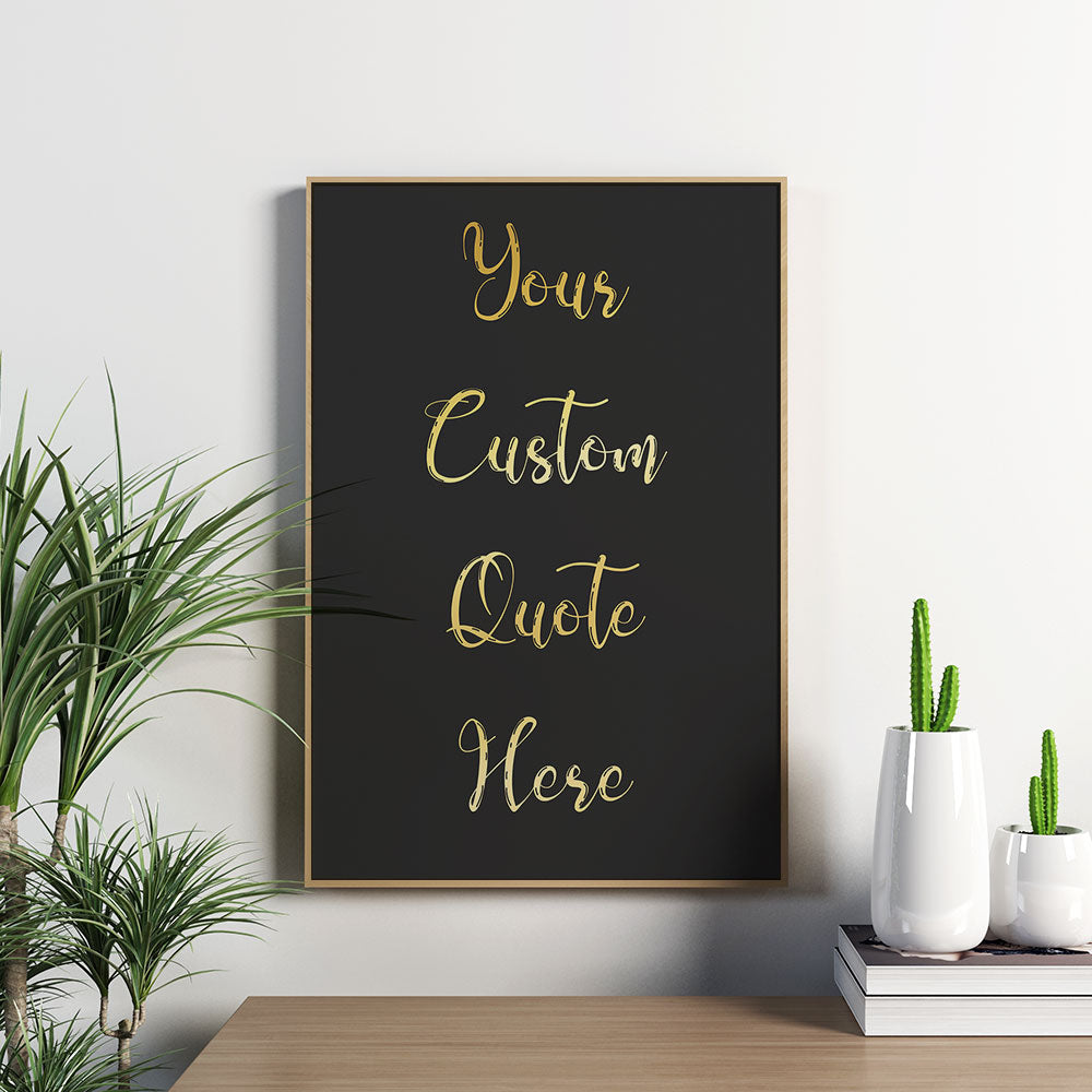 Framed black print with "Your Custom Quote Here" in elegant gold script, next to indoor plants.