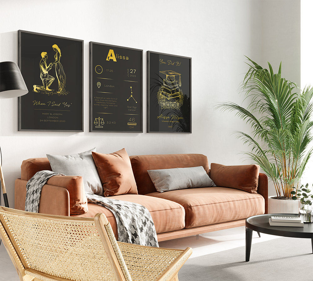 Living room wall adorned with personalized gold-on-black prints including a proposal silhouette and baby stats.